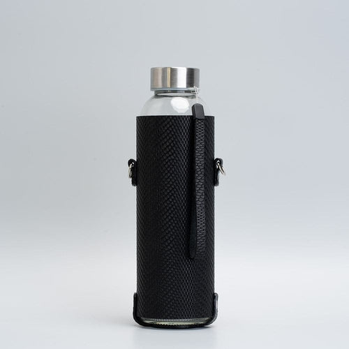 Leather water bottle holder with strap and glass bottle.