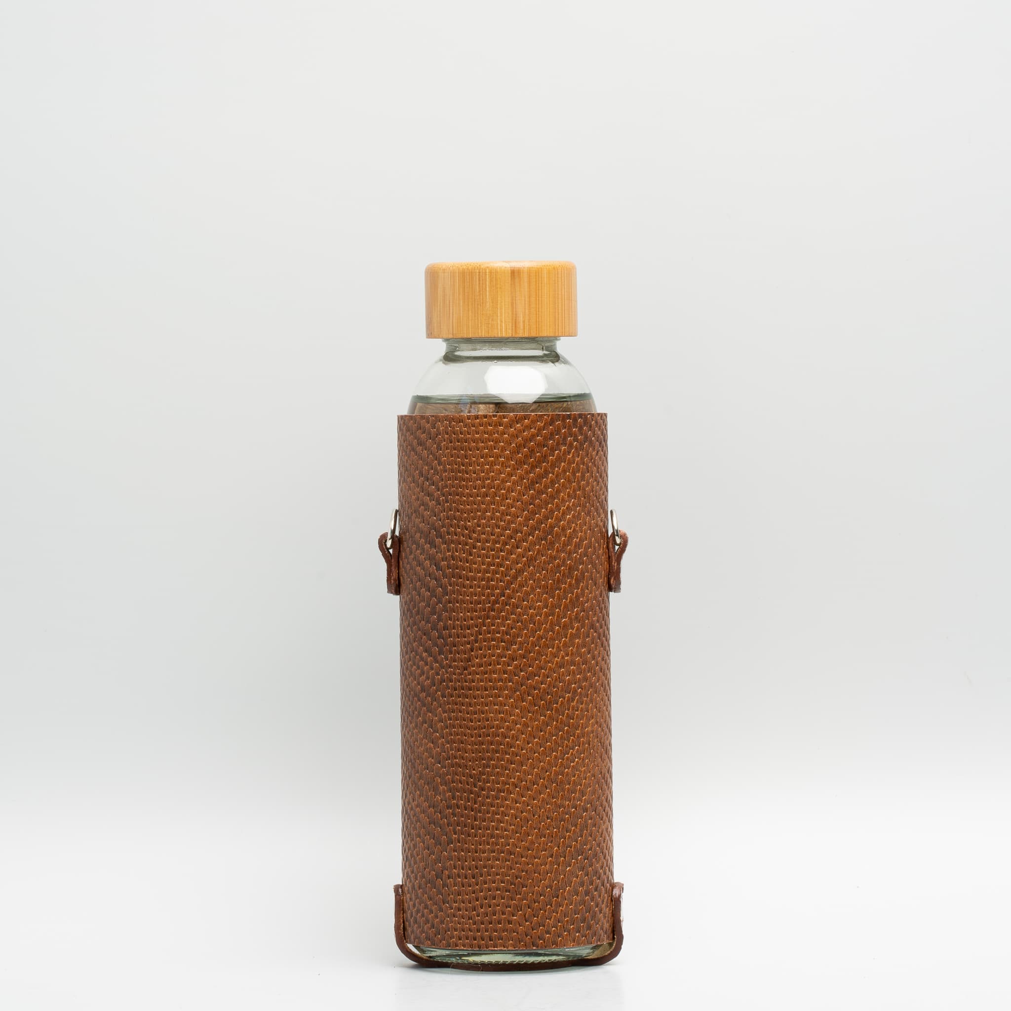Leather water bottle holder with strap and glass bottle.