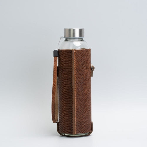 Leather water bottle holder with strap and glass bottle.