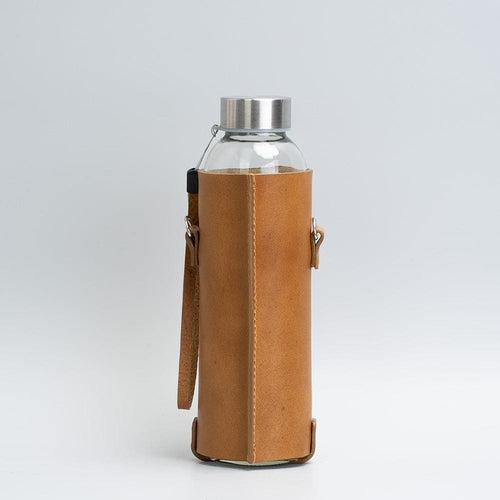 Leather water bottle holder with strap and glass bottle.