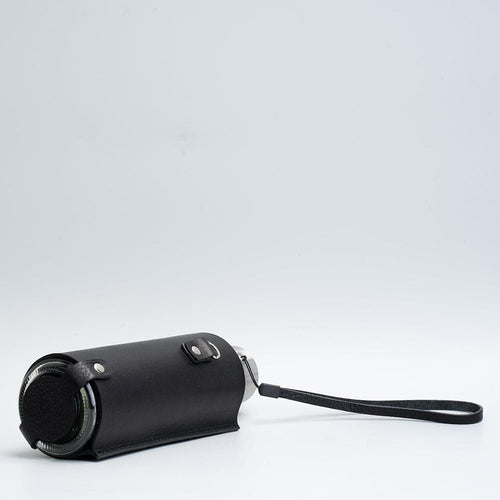 Leather water bottle holder with strap and glass bottle.